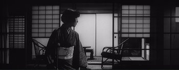 Movie still from “The Bad Sleep Well” (1960), directed by Akira Kurosawa – A woman in a kimono standing in front of an open door; Wide shot, Low angle