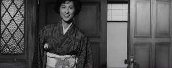 Movie still from “The Bad Sleep Well” (1960), directed by Akira Kurosawa – A woman in a kimono standing in front of a wooden door; Medium shot, Low angle