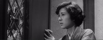Movie still from “The Bad Sleep Well” (1960), directed by Akira Kurosawa – A young woman holding a cell phone up to her face; Close Up shot, Low angle