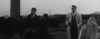 Movie still from “The Bad Sleep Well” (1960), directed by Akira Kurosawa – A group of people standing next to each other on top of a field; Medium shot, Over the shoulder angle
