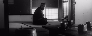 Movie still from “The Bad Sleep Well” (1960), directed by Akira Kurosawa – An older man sitting on the ground in a room; Medium shot, Low angle