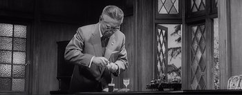 Movie still from “The Bad Sleep Well” (1960), directed by Akira Kurosawa – A man in a suit and tie holding a knife; Medium shot, Low angle
