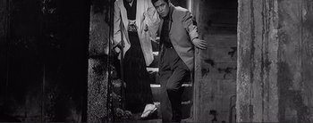 Movie still from “The Bad Sleep Well” (1960), directed by Akira Kurosawa – A black and white photo of a man and a woman climbing stairs; Medium shot, Low angle