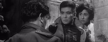 Movie still from “The Bad Sleep Well” (1960), directed by Akira Kurosawa – A man looking at another man in a trench coat; Medium shot, Over the shoulder angle