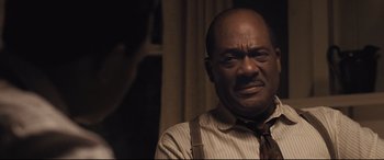 Movie still from “The Banker” (2020), directed by George Nolfi – An older man wearing a striped shirt and a tie; Close Up shot, Over the shoulder angle