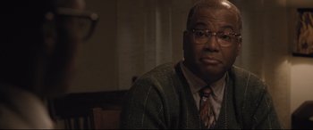 Movie still from “The Banker” (2020), directed by George Nolfi – An older man wearing glasses and a tie; Close Up shot, Over the shoulder angle