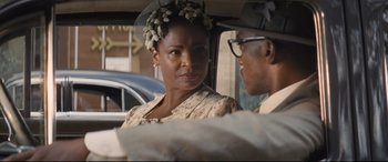 Movie still from “The Banker” (2020), directed by George Nolfi – A woman wearing a flower crown in the back of a car; Close Up shot, Over the shoulder angle