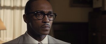 Movie still from “The Banker” (2020), directed by George Nolfi – A person wearing glasses and a suit; Close Up shot, Low angle