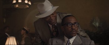 Movie still from “The Banker” (2020), directed by George Nolfi – Two men in suits and hats posing for a picture; Close Up shot, Over the shoulder angle