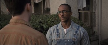 Movie still from “The Banker” (2020), directed by George Nolfi – A man wearing glasses and a plaid shirt is standing outside; Close Up shot, Over the shoulder angle