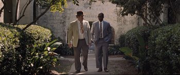 Movie still from “The Banker” (2020), directed by George Nolfi – A couple of men walking down a sidewalk next to each other; Wide shot, Over the shoulder angle