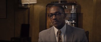 Movie still from “The Banker” (2020), directed by George Nolfi – A man in a suit and tie wearing glasses; Close Up shot, Over the shoulder angle