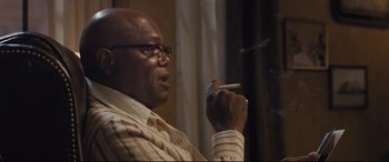 Movie still from “The Banker” (2020), directed by George Nolfi – An older man smoking a cigarette in a room; Close Up shot, Low angle