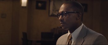 Movie still from “The Banker” (2020), directed by George Nolfi – A man in a suit and tie wearing glasses; Close Up shot, Over the shoulder angle