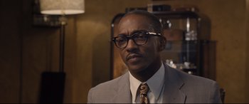 Movie still from “The Banker” (2020), directed by George Nolfi – A man in a suit and tie wearing glasses; Close Up shot, Low angle