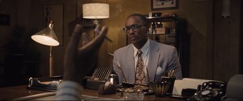 Movie still from “The Banker” (2020), directed by George Nolfi – A man sitting at a table smoking a cigarette; Close Up shot, Over the shoulder angle