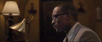 Movie still from “The Banker” (2020), directed by George Nolfi – A person wearing glasses and a tie; Close Up shot, Over the shoulder angle
