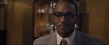 Movie still from “The Banker” (2020), directed by George Nolfi – A person wearing a suit and glasses; Close Up shot, Over the shoulder angle