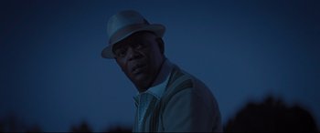 Movie still from “The Banker” (2020), directed by George Nolfi – A man wearing a hat standing in the dark at night; Close Up shot, Low angle