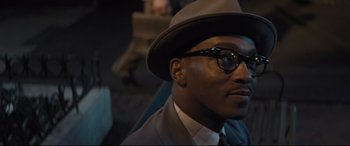 Movie still from “The Banker” (2020), directed by George Nolfi – A person wearing a hat and glasses; Close Up shot, High angle