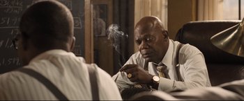 Movie still from “The Banker” (2020), directed by George Nolfi – An older man smoking a cigarette in front of another man; Close Up shot, Over the shoulder angle