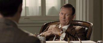 Movie still from “The Banker” (2020), directed by George Nolfi – A person wearing a suit and tie; Close Up shot, Over the shoulder angle