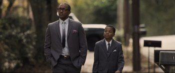 Movie still from “The Banker” (2020), directed by George Nolfi – A man and a boy in suits walking down a street; Medium shot, Low angle