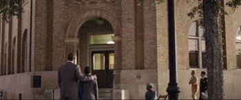 Movie still from “The Banker” (2020), directed by George Nolfi – A couple of people standing in front of a building; Wide shot, Low angle