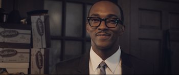 Movie still from “The Banker” (2020), directed by George Nolfi – A person wearing a suit and glasses; Close Up shot, Low angle