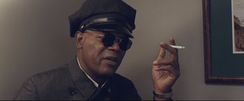 Movie still from “The Banker” (2020), directed by George Nolfi – A man in a hat and sunglasses smoking a cigarette; Close Up shot, Low angle
