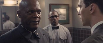 Movie still from “The Banker” (2020), directed by George Nolfi – Two men standing next to each other in front of a wall; Close Up shot, Over the shoulder angle