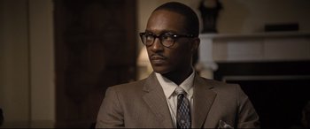 Movie still from “The Banker” (2020), directed by George Nolfi – A man in a suit and tie wearing glasses; Close Up shot, Over the shoulder angle