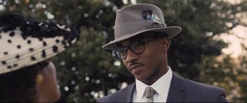 Movie still from “The Banker” (2020), directed by George Nolfi – A person wearing a hat and glasses; Close Up shot, Over the shoulder angle
