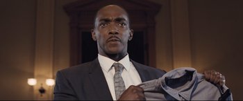 Movie still from “The Banker” (2020), directed by George Nolfi – A man in a suit and tie holding a jacket; Close Up shot, Low angle