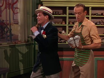 Movie still from “The Barkleys of Broadway” (1949), directed by Charles Walters – A man in a suit and a man in a hat are dancing in a kitchen; Medium shot, Over the shoulder angle