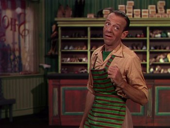 Movie still from “The Barkleys of Broadway” (1949), directed by Charles Walters – A man wearing an apron standing next to a shoe store; Medium shot, Over the shoulder angle