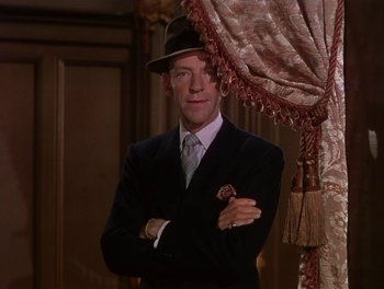 Movie still from “The Barkleys of Broadway” (1949), directed by Charles Walters – A man in a suit and hat standing in front of a curtain; Medium shot, High angle