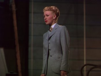 Movie still from “The Barkleys of Broadway” (1949), directed by Charles Walters – A woman wearing a suit and tie standing in front of a building; Medium shot, Low angle