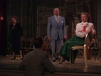 Movie still from “The Barkleys of Broadway” (1949), directed by Charles Walters – A group of people on a stage with a man in a suit; Wide shot, Over the shoulder angle