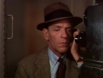 Movie still from “The Barkleys of Broadway” (1949), directed by Charles Walters – A man wearing a suit and a hat talking on a phone; Close Up shot, High angle