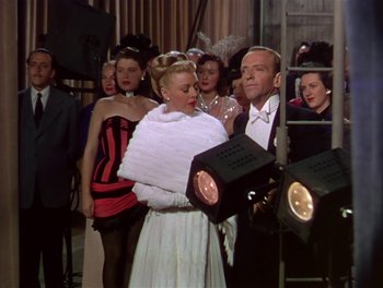 Movie still from “The Barkleys of Broadway” (1949), directed by Charles Walters – A man and a woman are standing next to each other in front of a group of people; Medium shot, Low angle