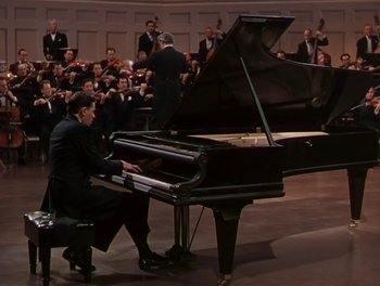Movie still from “The Barkleys of Broadway” (1949), directed by Charles Walters – A man sitting at a grand piano in front of a crowd; Wide shot, High angle