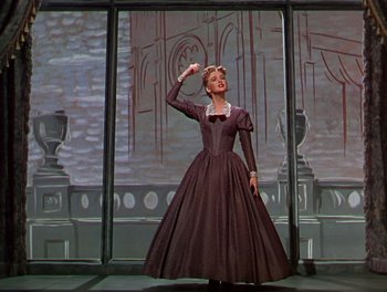 Movie still from “The Barkleys of Broadway” (1949), directed by Charles Walters – A woman dressed in a long dress is standing in front of a window; Medium shot, Low angle
