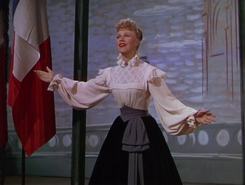 Movie still from “The Barkleys of Broadway” (1949), directed by Charles Walters – A woman wearing a white blouse and a black skirt; Medium shot, Low angle