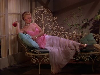 Movie still from “The Barkleys of Broadway” (1949), directed by Charles Walters – A woman in a pink dress is sitting on a chair; Wide shot, High angle