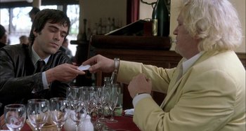 Movie still from “The Beat That My Heart Skipped” (2005), directed by Jacques Audiard – Two men sitting at a table in front of wine glasses; Medium shot, Over the shoulder angle