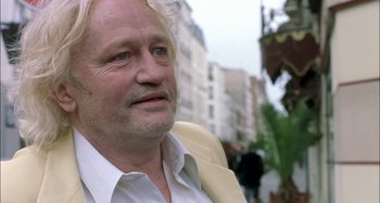 Movie still from “The Beat That My Heart Skipped” (2005), directed by Jacques Audiard – An older man in a white shirt and a white jacket; Close Up shot, Over the shoulder angle