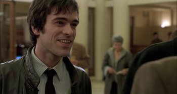 Movie still from “The Beat That My Heart Skipped” (2005), directed by Jacques Audiard – A man in a suit and tie smiling for the camera; Close Up shot, Over the shoulder angle