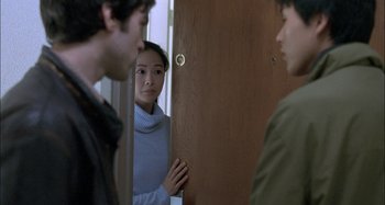 Movie still from “The Beat That My Heart Skipped” (2005), directed by Jacques Audiard – A woman standing in front of two men in front of a door; Medium shot, Over the shoulder angle