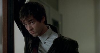 Movie still from “The Beat That My Heart Skipped” (2005), directed by Jacques Audiard – A man in a suit and tie standing in front of a wall; Close Up shot, Over the shoulder angle